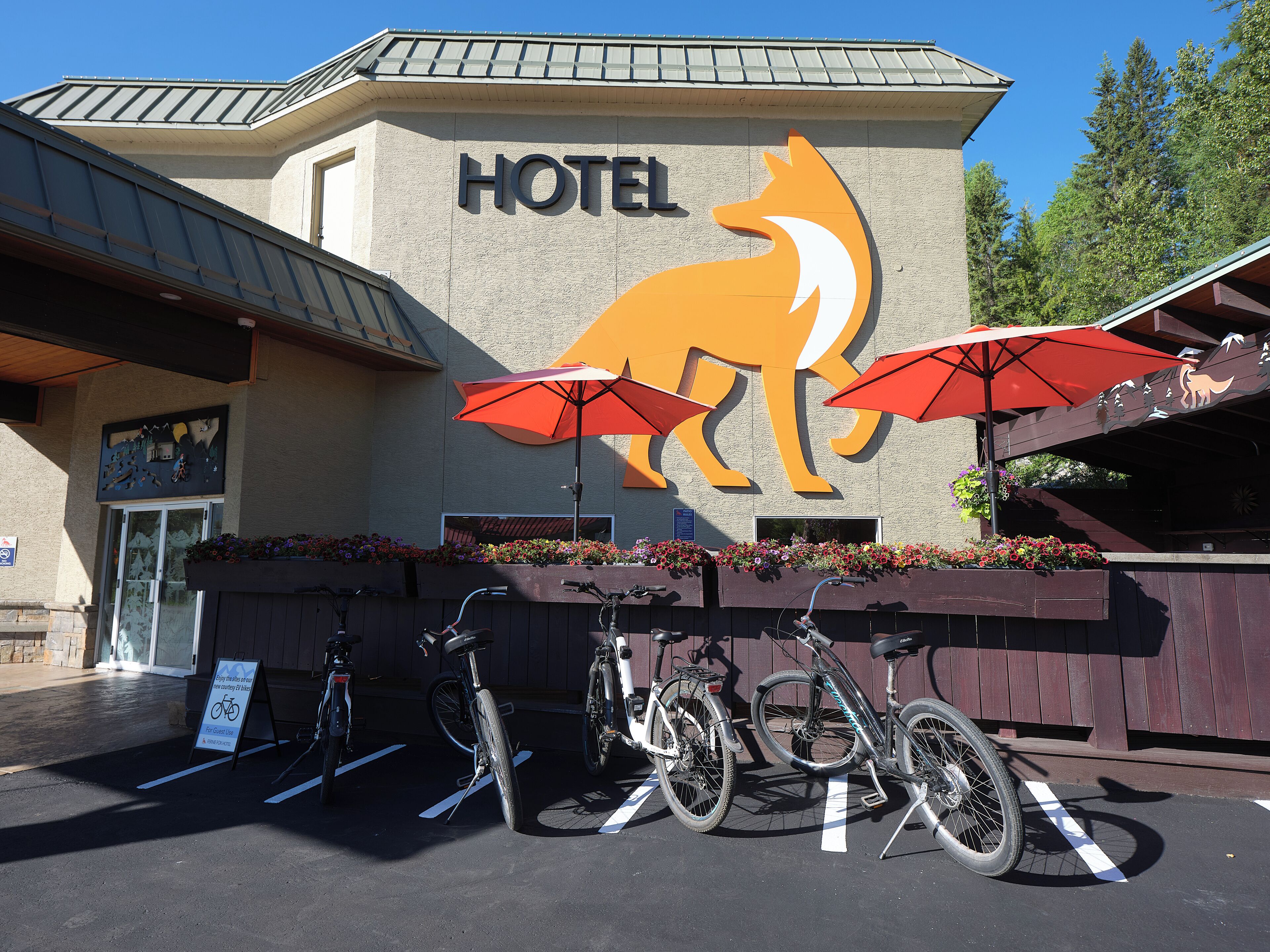A hotel with a large logo of a horse and rider, bicycles parked in front, and a sign indicating a bike rental service.