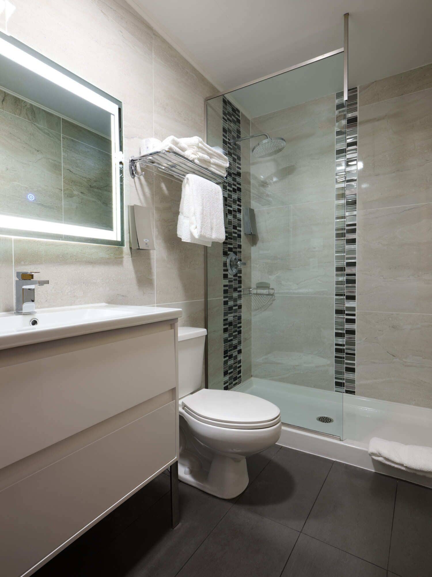Une salle de bain moderne avec une douche à parois de verre, des toilettes et un meuble-lavabo avec un miroir.