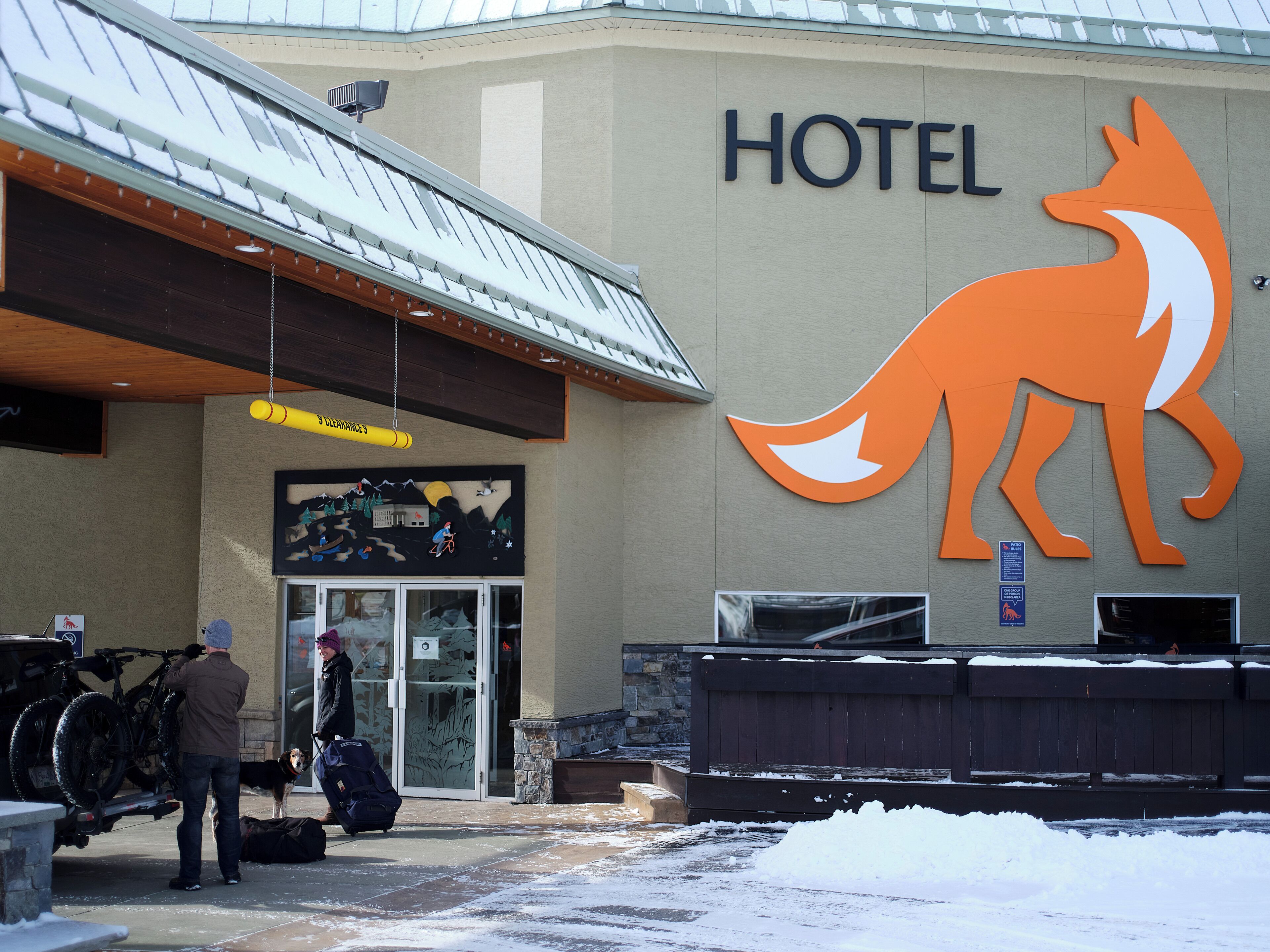 A hotel with a large fox logo, a covered entrance, and a snow-covered ground.