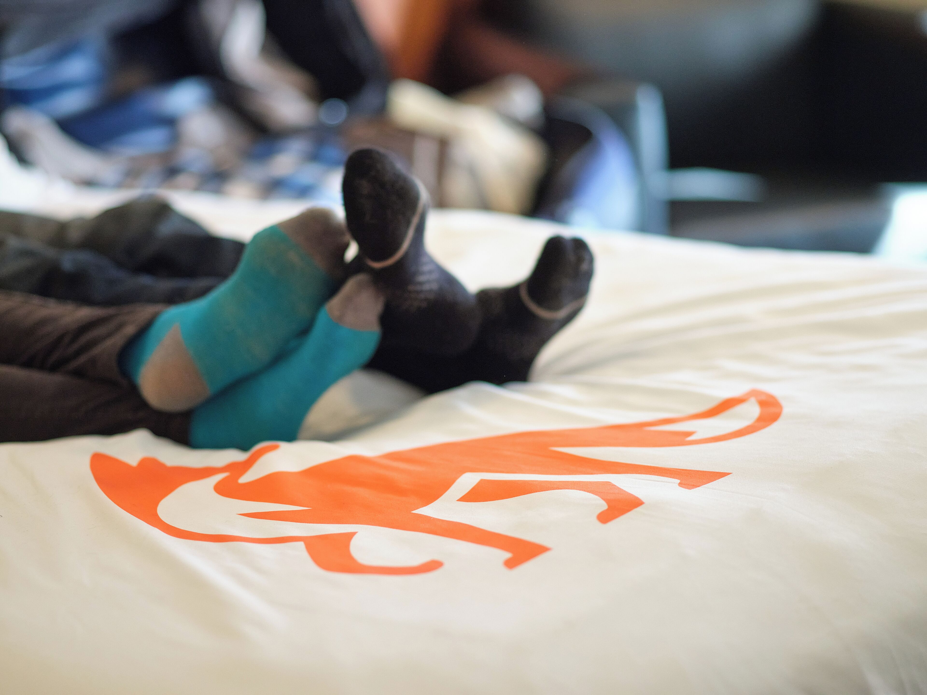 A bed with a white sheet featuring an orange dragon design.
