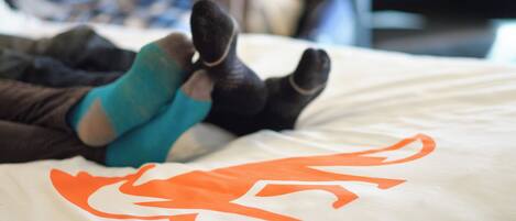 A bed with a white sheet featuring an orange dragon design.
