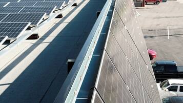 A solar panel array on a building with a mountainous backdrop.