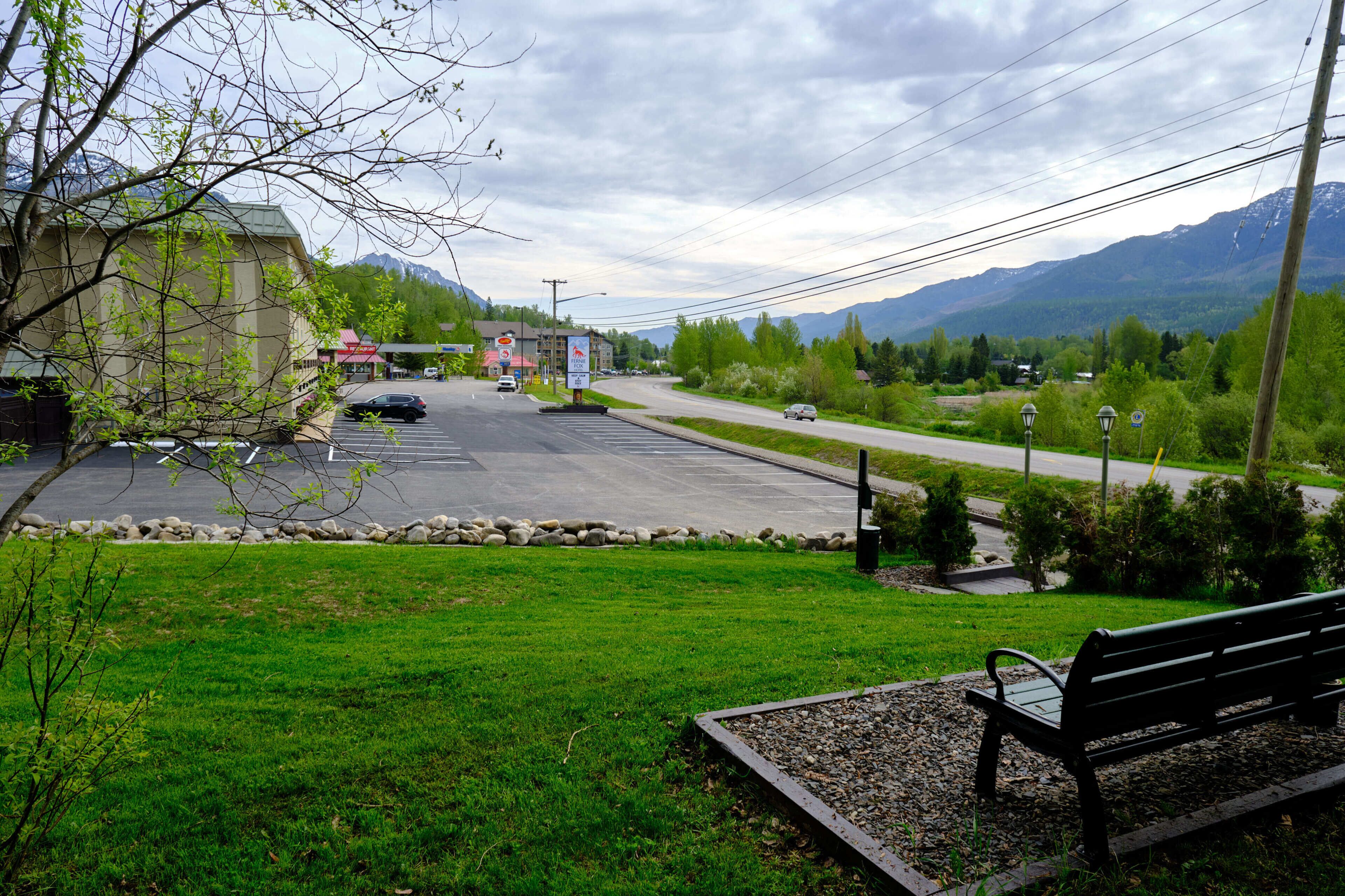 A parking lot with a bench, a building, and mountains in the background.