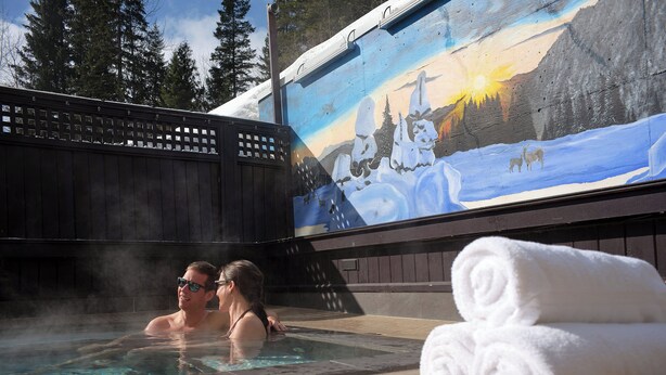 A hot tub with a painted mural of a snowy landscape and a wooden deck. - Fernie Fox Hotel (Fernie)