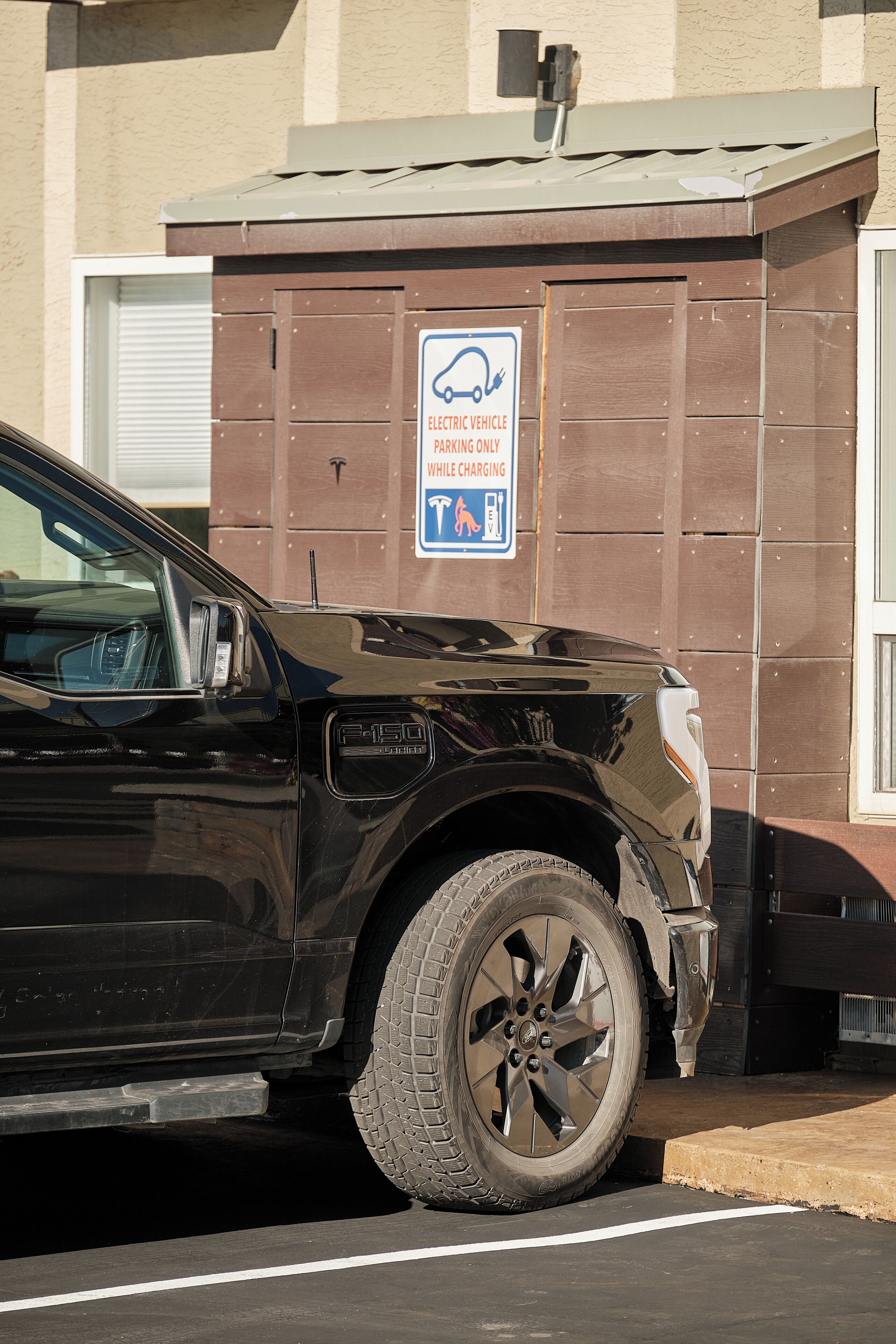 Ein schwarzer SUV steht auf einem Parkplatz, auf dessen Schild nur Parkplätze für Elektrofahrzeuge ausgewiesen sind.