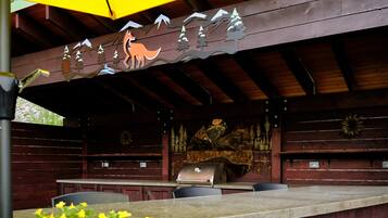 An outdoor patio with a wooden table and chairs, a grill, and a decorative mural.