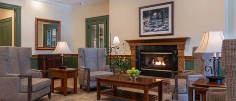 A cozy living room with a fireplace, comfortable seating, and a decorative painting.