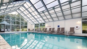 Una piscina interior con techo de vidrio, sillas de descanso y un cartel que indica 'No Diving'.