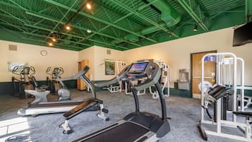 Un gimnasio con cintas de correr, elípticas y equipo de pesas.