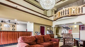 A hotel lobby with a red sofa, a coffee station, and a reception desk.