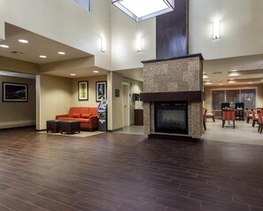 A spacious lobby with a fireplace, seating area, and a dining section. - Comfort Suites Tulsa Central (Tulsa)