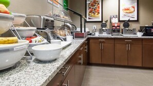 A buffet setup with various food items, including fruits, bread, and beverages.