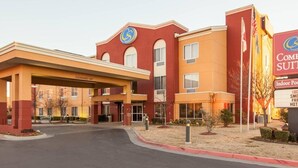 A hotel with a red and yellow facade, a covered entrance, and a sign indicating indoor pool and free breakfast.