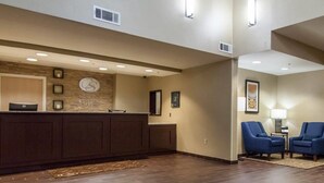 A hotel reception area with a wooden reception desk, a clock, and a framed picture on the wall.