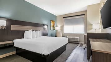 Ett modernt hotellrum med en stor säng, sängbord, ett skrivbord och ett fönster med persienner.
