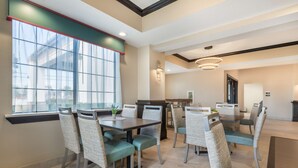 A modern dining area with a large window, a central table, and wicker chairs.