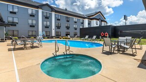 A hotel with a swimming pool, outdoor seating, and a large building with multiple windows. - Best Western Prime Inn & Suites (Poteau)