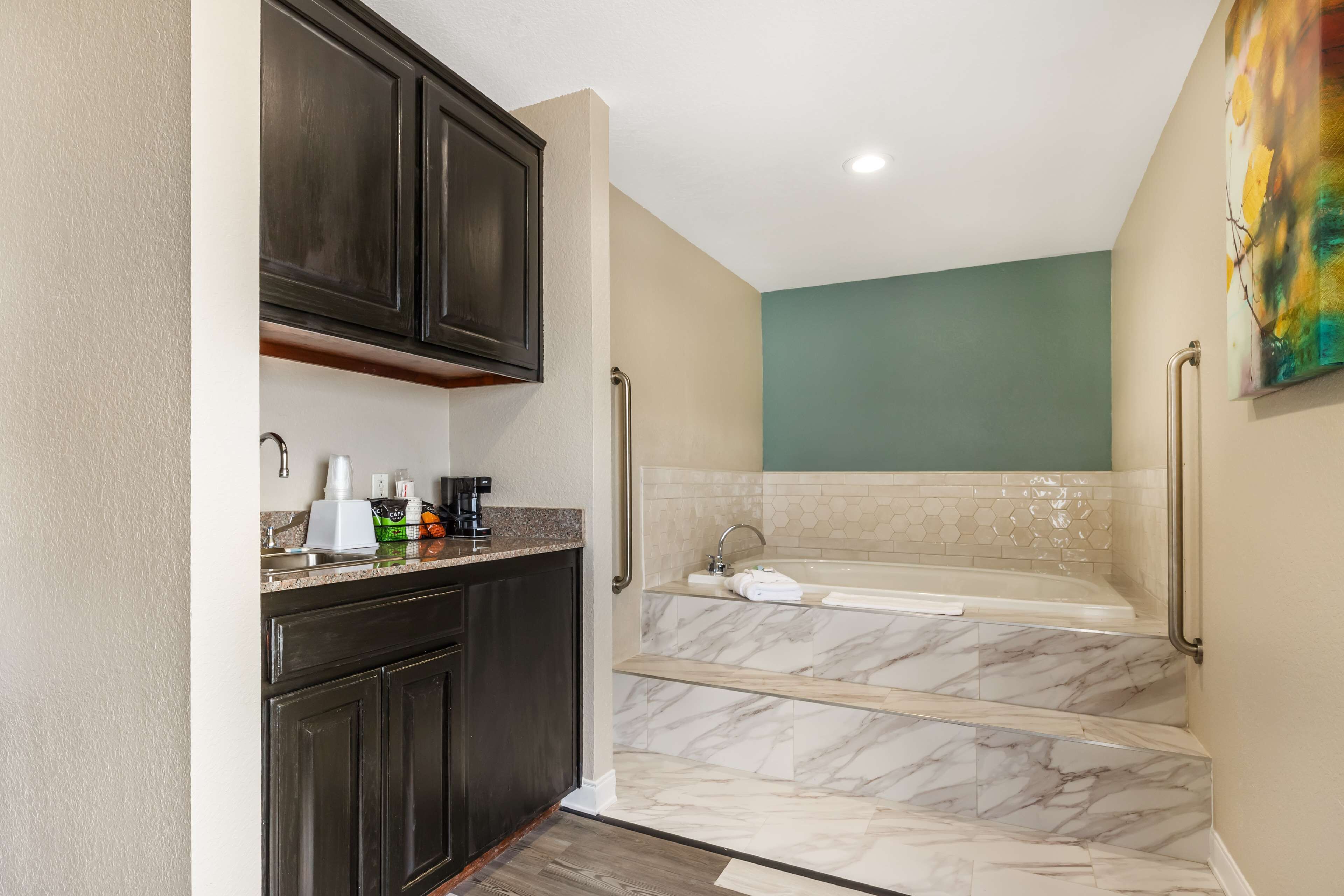Un baño con piso de mármol, una bañera y un lavamanos.