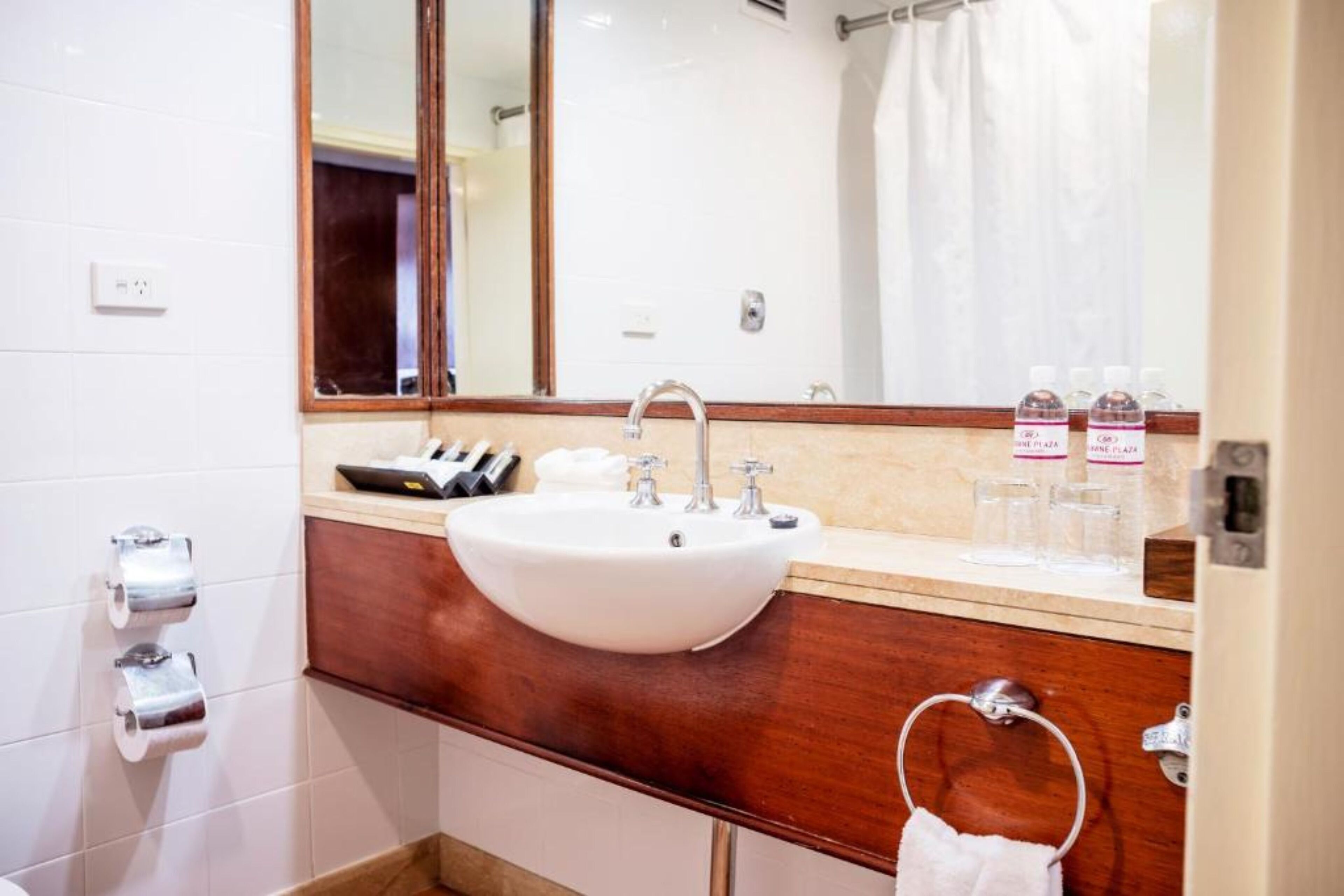 A bathroom with a white sink, a mirror, a towel ring, and a toilet.