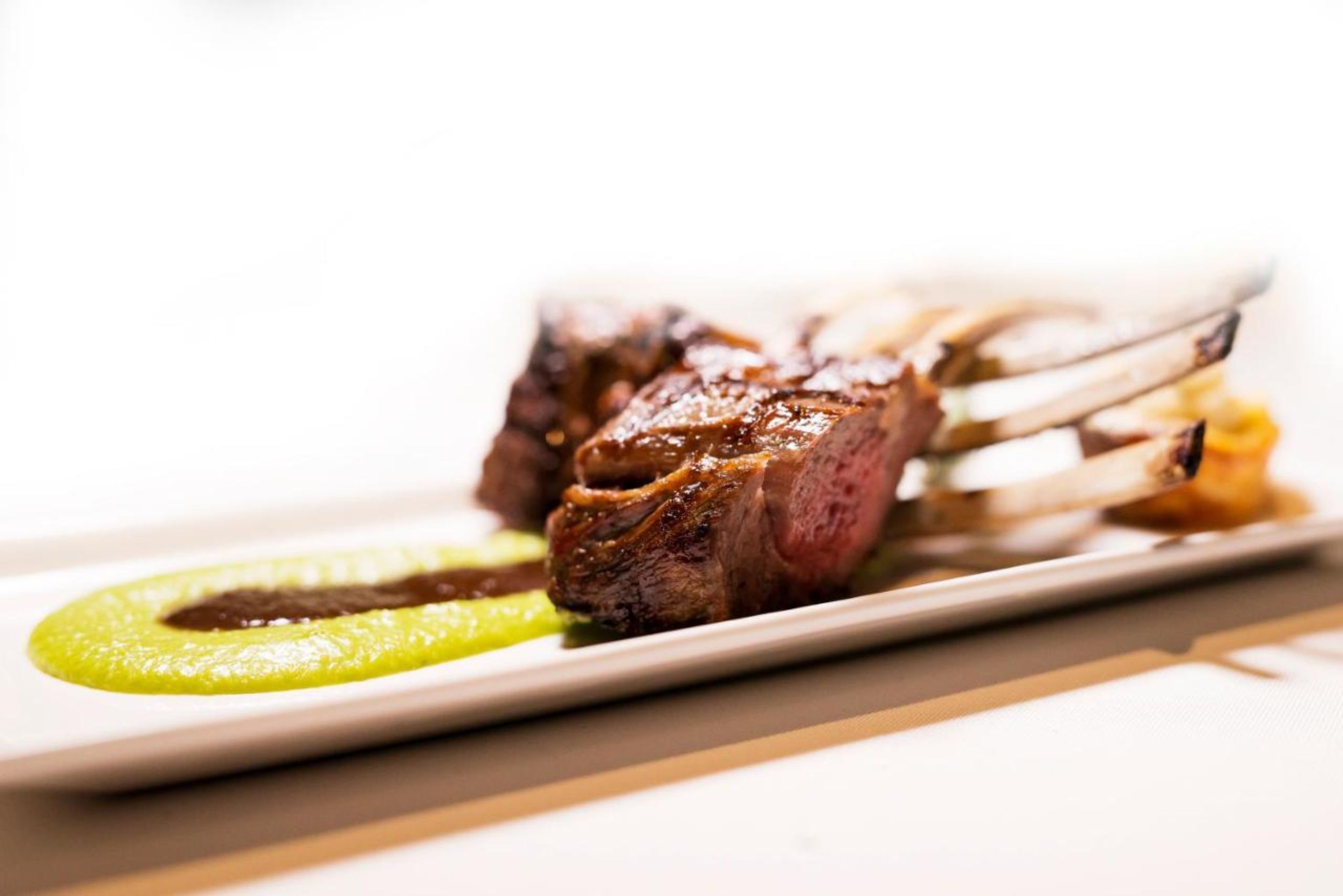 A plate of food with a piece of meat and a green sauce.