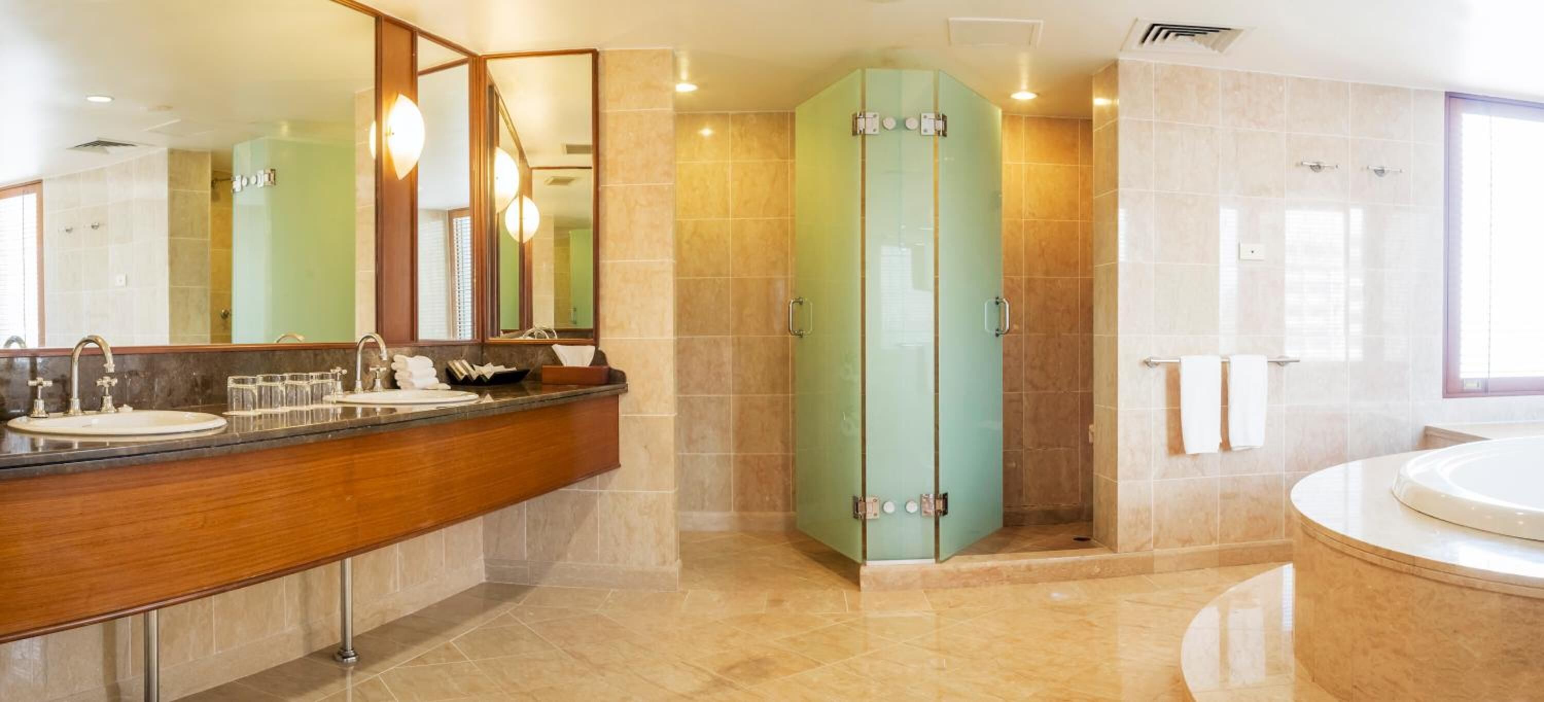 A modern bathroom with a wooden vanity, a large mirror, a glass shower enclosure, and a separate bathtub area.
