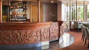 Un espace bar doté d’un comptoir en bois incurvé et offrant une vue sur l’extérieur grâce à de grandes fenêtres.
