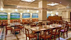 A spacious dining area with high ceilings, chandeliers, and a mural of a landscape. Tables are set with chairs and centerpieces. - Landmark Hotel (Dubai)
