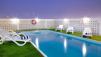 Una piscina al aire libre, sillones reclinables de piscina