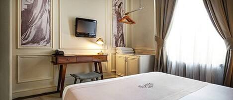 A hotel room with a bed, a desk, a chair, a television, and a window with curtains.