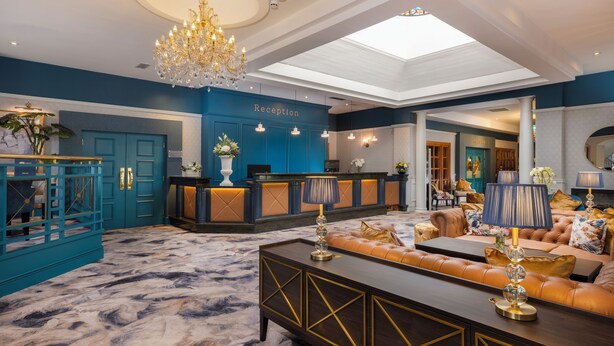 A reception area with a blue wall, a chandelier, and a reception desk. - Ardboyne Hotel (Navan)