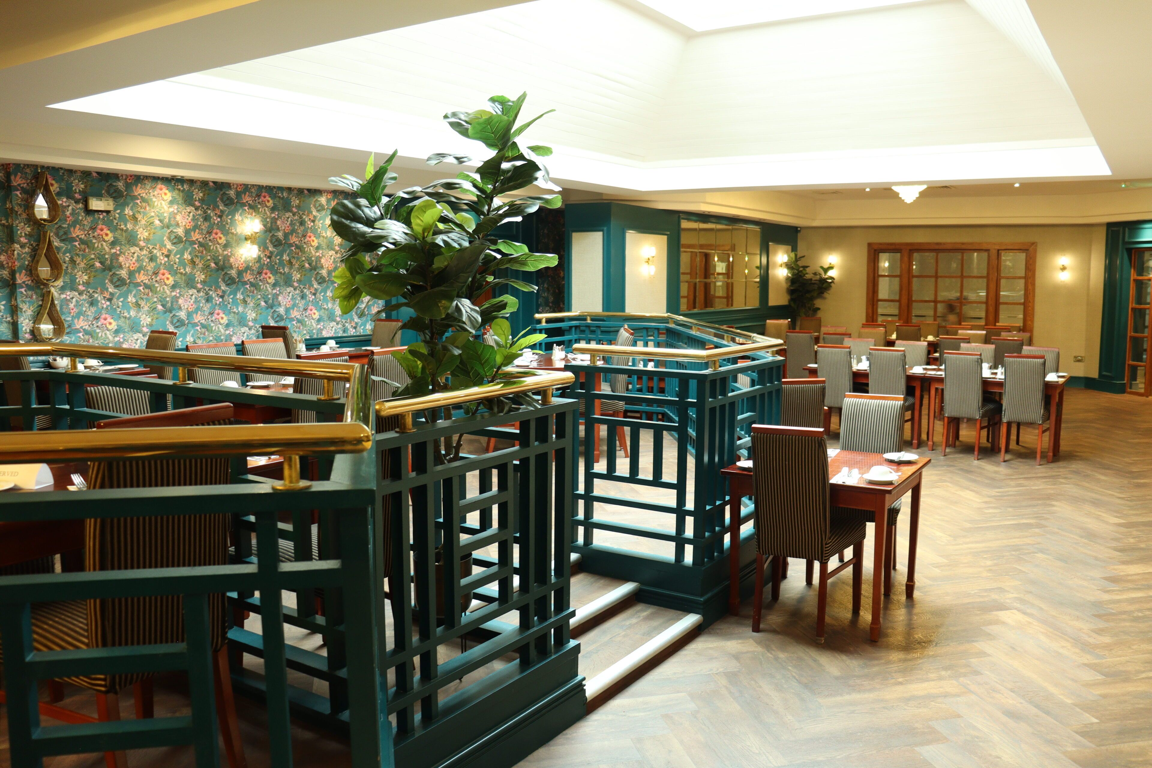 Un restaurante espacioso con techos altos, una escalera central y diversas opciones de asientos, incluyendo mesas y sillas.