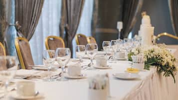 Une table de banquet dressée pour un événement formel, avec des chaises, de la verrerie et un gâteau à étages.
