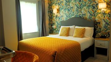 A hotel room with a bed, a nightstand, a chair, and a window with curtains.