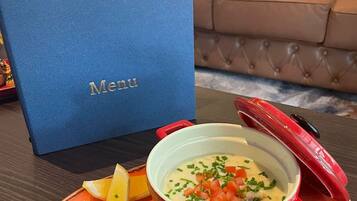 Menú del Hotel Ardoyne, mostrando un bol de sopa con cebollín y tomates en cubitos, acompañado de rebanadas de pan y un gajo de limón sobre un plato naranja.