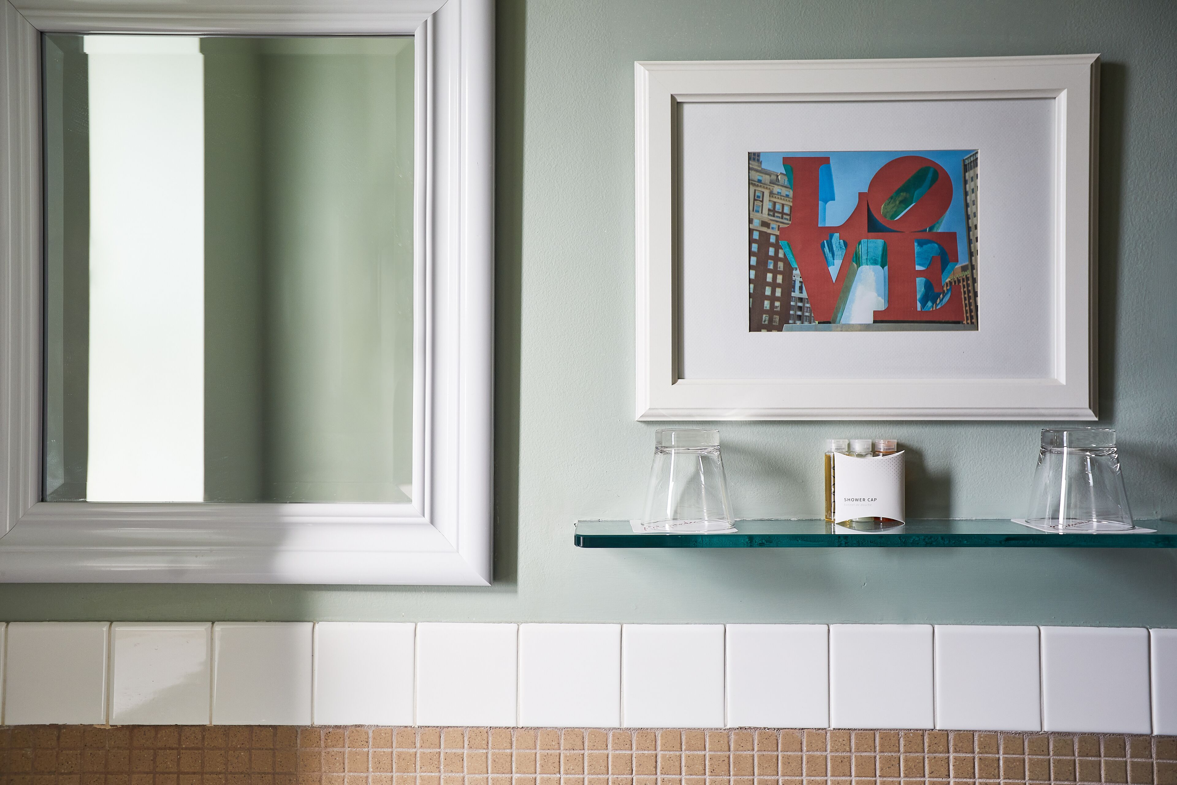 A framed artwork with the word "LOVE" on a bathroom wall.