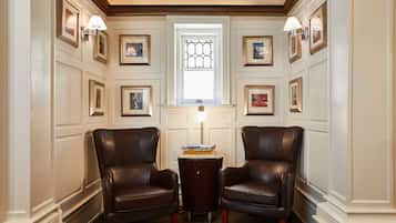 A room with two leather armchairs, a small table with books, and a window with decorative glass.