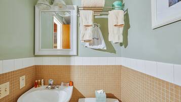 A bathroom with a sink, mirror, towel rack, and toiletries.