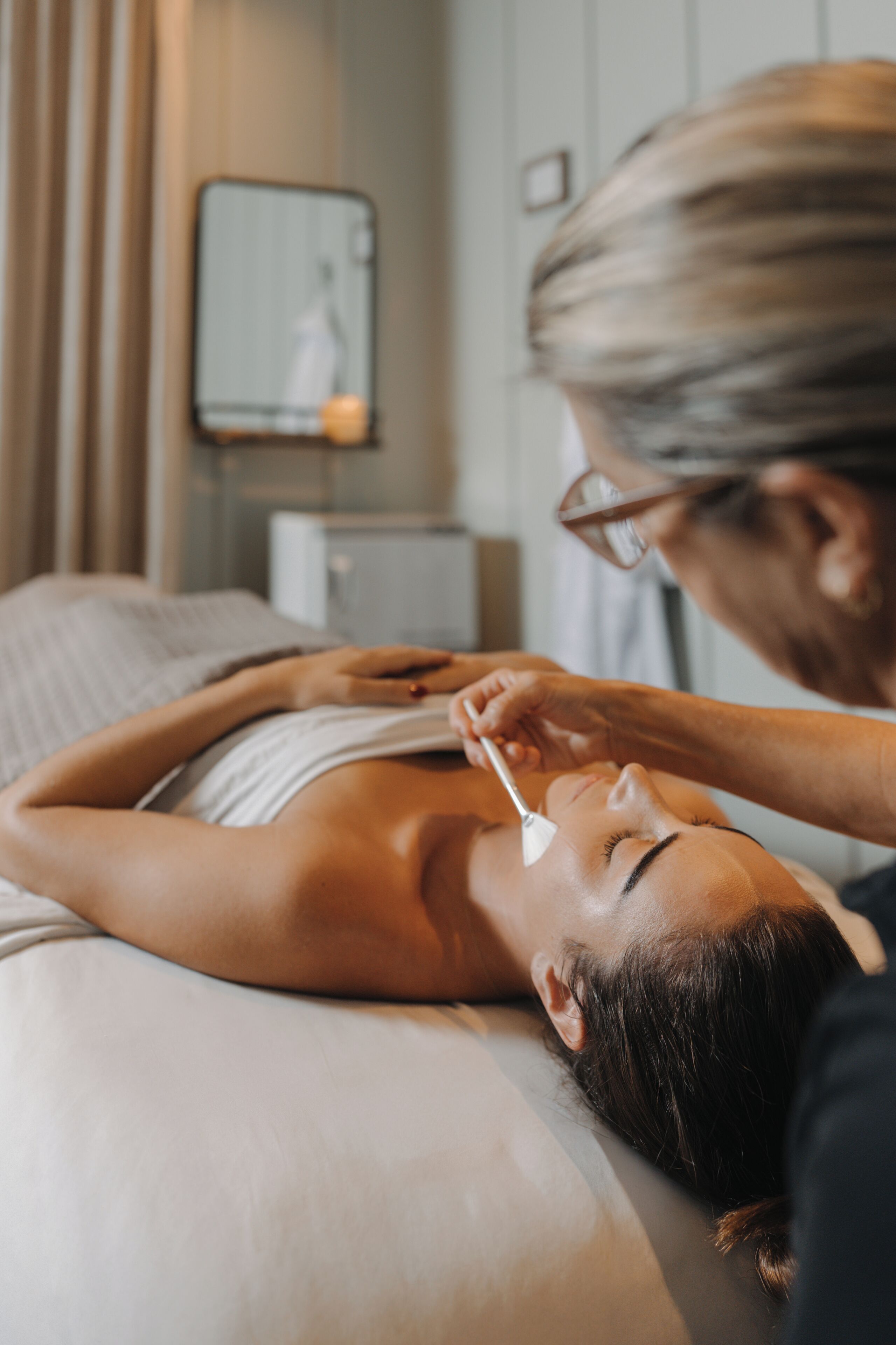A person lying on a bed receiving a facial treatment.