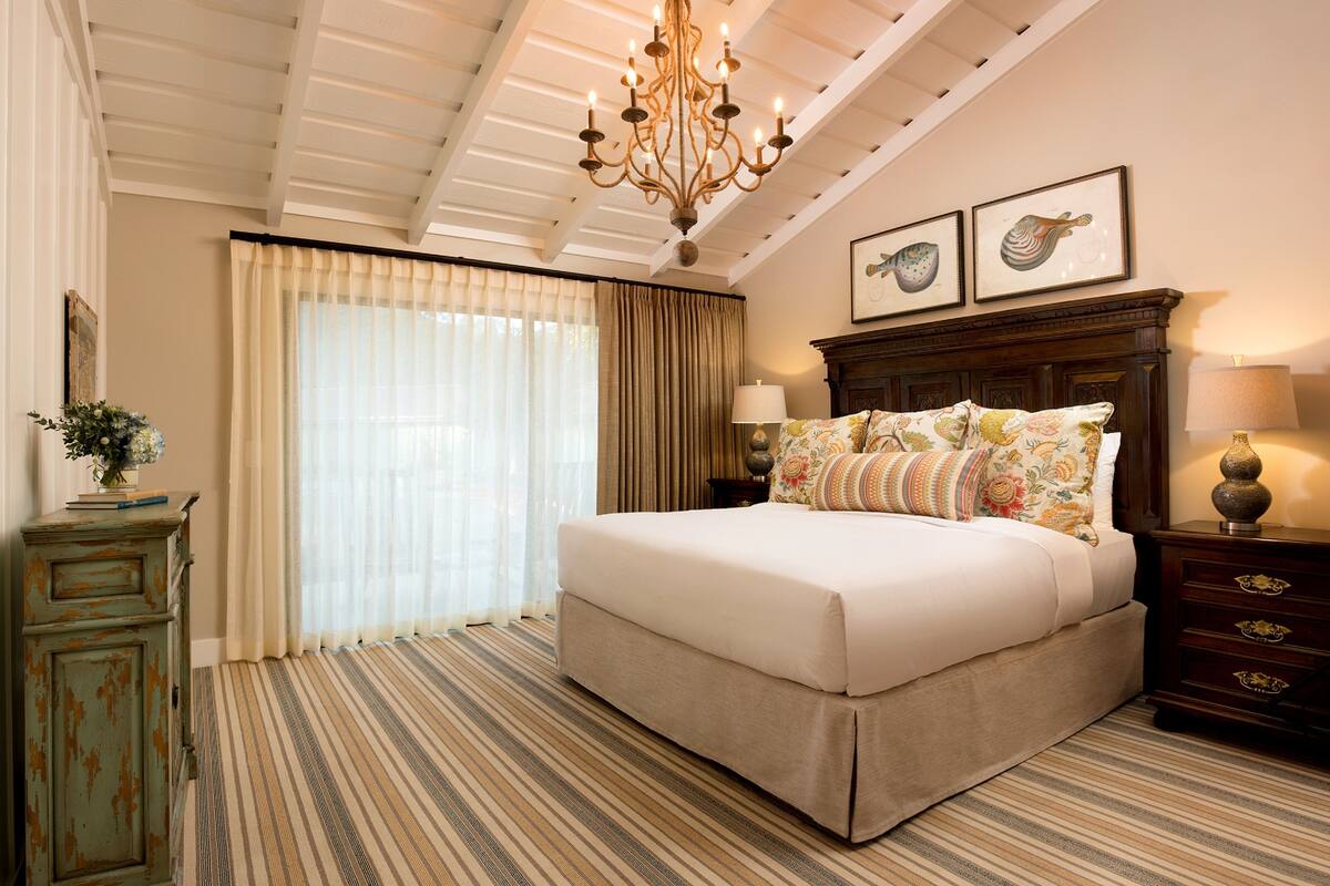 A bedroom with a large bed, a chandelier, a dresser, and a nightstand.