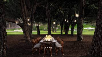 An outdoor dining table set up in a forested area with trees surrounding it.