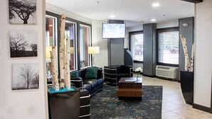 Sala moderna com sofá, mesa de centro e elementos decorativos como bétulas e obras de arte.