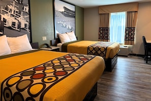 Habitación de hotel con dos camas, un ventanal con cortinas, un escritorio y una silla.