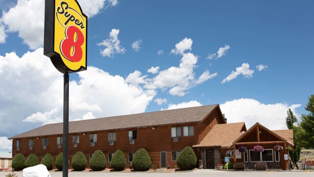 A Super 8 motel with a large sign, a brick building, and neatly trimmed bushes.