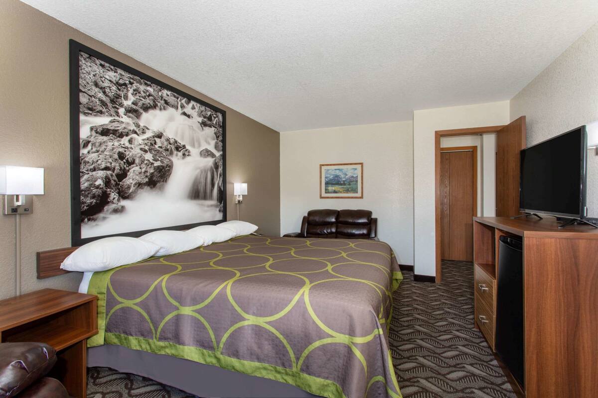 Ein Hotelzimmer mit einem großen Bett, einem Fernseher, einem Schreibtisch und einem Badezimmer.