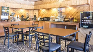 A wooden interior with tables and chairs, a coffee machine, a microwave, and a refrigerator.