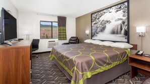 A hotel room with a bed, a desk, a chair, a TV, a window with a view, and a painting of a waterfall.