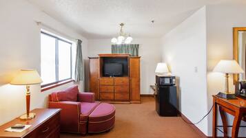 Habitación de hotel con sofá, televisión, escritorio, lámpara y microondas.