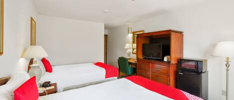 Une chambre d’hôtel avec deux lits, une télévision, un réfrigérateur et un bureau avec une chaise.