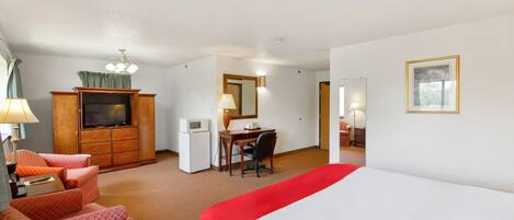A hotel room with a bed, a desk, a television, a microwave, and a wardrobe.