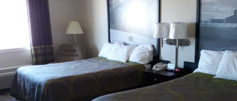 A hotel room with two beds, a nightstand with a lamp, a window with curtains, and a painting on the wall.